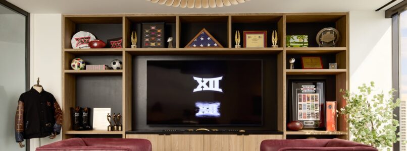 Lounge with red chairs and a Big 12 logo display on built-in shelving