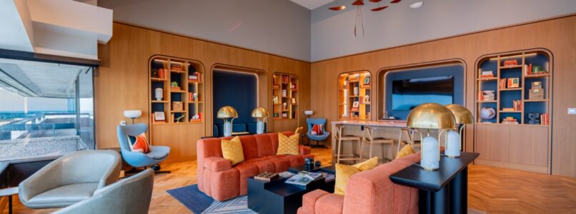 Lounge with orange sofas, built-in bookshelves and a red mobile sculpture at the Constellation Club