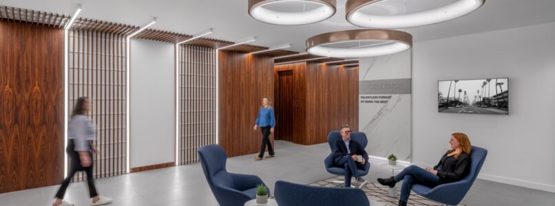 Lobby lounge with blue chairs under ring pendant lights in the Conti Capital office