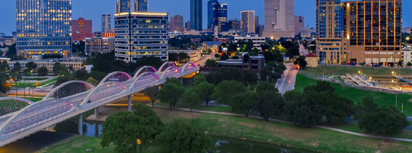 Fort Worth skyline at dusk with the Trinity River and an arched bridge