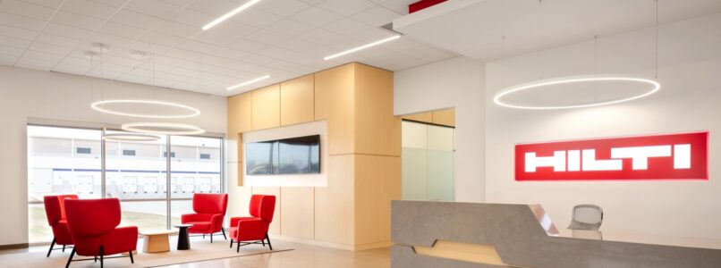 Hilti reception desk with red lounge chairs and ring pendant lights