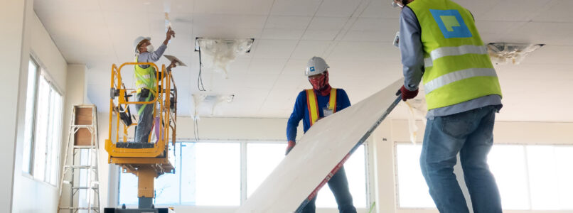 Construction workers installing ceiling panels from a scissor lift in an interior build-out
