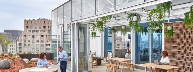 Rooftop office terrace with picnic tables, planters and people working outdoors