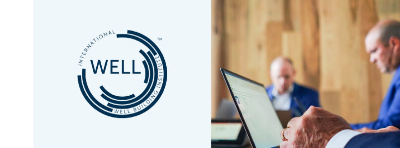 WELL Building Standard logo beside business professionals working at a laptop