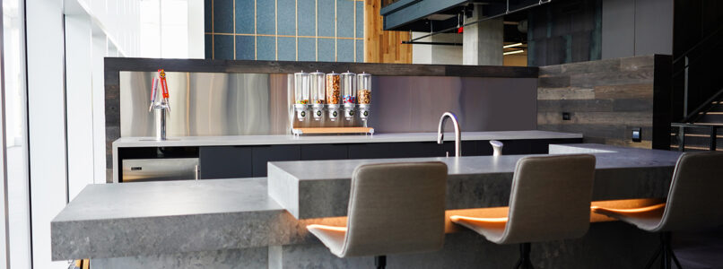 Modern kitchen island with bar stools and pendant lighting in an office interior