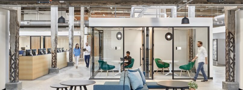 Open lounge with blue sofas and glass meeting rooms in a restored warehouse in the Simplifi office