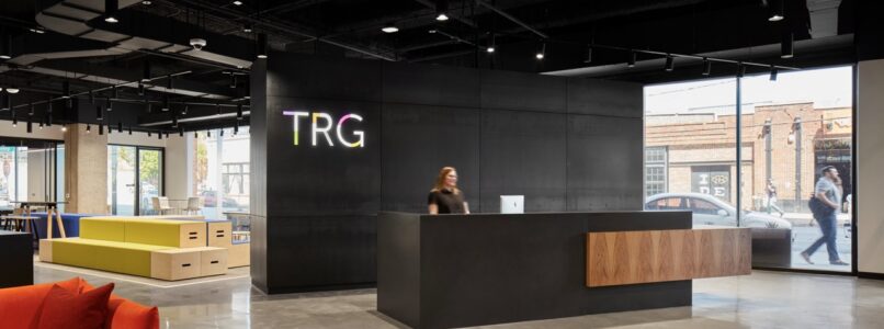 TRG reception desk with black logo wall and colorful lounge seating